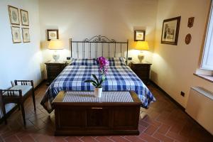 1 dormitorio con 1 cama con un jarrón de flores sobre una mesa en Appartamento AVA nell'antica dimora di Fulignano, en San Gimignano