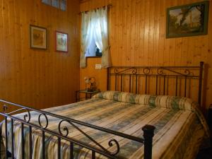 1 dormitorio con cama de metal en una habitación con paredes de madera en B&B La Quercia, en Orte