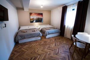two beds in a room with a table and a dining room at New rooms & apartments in Ljubljana in Ljubljana