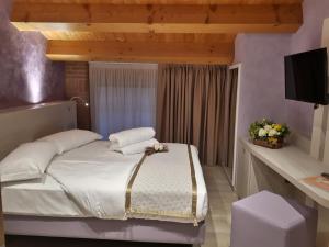 Schlafzimmer mit einem Bett mit weißer Bettwäsche und einem TV in der Unterkunft Agriturismo Cabrele in Santorso