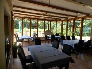 uma sala de jantar com mesas, cadeiras e janelas em Angelhof Weseloh em Karolei