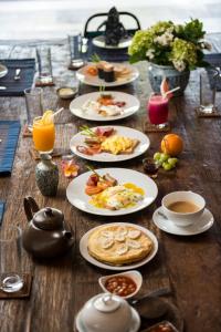 una mesa de madera con platos de desayuno. en Villa Tiga Puluh, en Seminyak