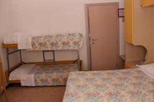 リミニにあるPensione Fiorella Riminiの二段ベッド2台とドアが備わる小さな客室です。
