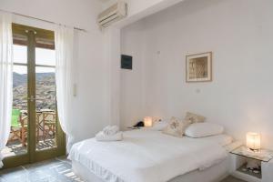 a white bedroom with a bed and a balcony at Agnanti Traditional in Kastron