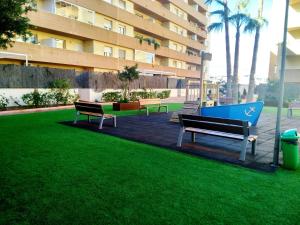 ロケタス・デ・マルにあるSalinas Comfortの建物前の芝生に座る三つの公園ベンチ