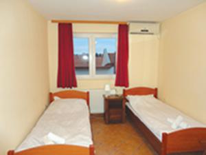 a small room with two beds and a window at Prenoćište "Magnus" in Slavonski Brod