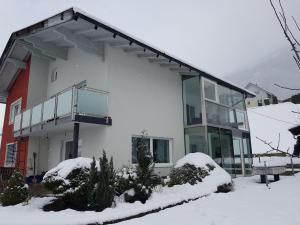 a white house with glass windows in the snow at Ferienwohnung Gurabic in Maurach