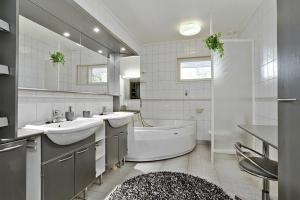 ein weißes Badezimmer mit zwei Waschbecken und einer Badewanne und einer Badewanne in der Unterkunft Villa SUNSET in Malax + 30 Fotos