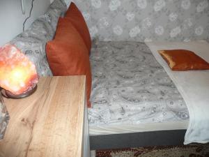 ブダペストにあるLaky9 Apartmanのベッド(オレンジ色の枕、木製テーブル付)
