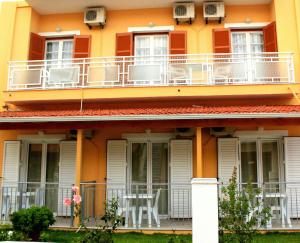 um edifício laranja com cadeiras numa varanda em Rantos Apartments em Kavos