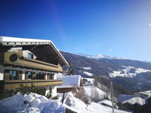 ein Haus auf einem verschneiten Hügel mit einem Berg in der Unterkunft AppHaus Sonne in Heiligenblut