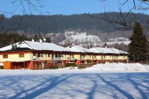 a building covered in snow next to a snow covered field at Promenáda Lipno in Lipno nad Vltavou