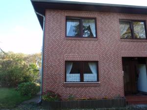 ein rotes Backsteinhaus mit einem Fenster mit einem Vorhang in der Unterkunft Ferienwohnung "Romaker" in Jeersdorf