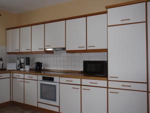 a kitchen with white cabinets and a white refrigerator at Ferienwohnung "Romaker" in Jeersdorf