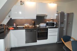 cocina con armarios blancos y nevera de acero inoxidable en Ferienwohnung "Haus 10", en Essen