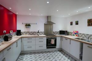 a kitchen with white cabinets and a red wall at Le Charlot in Saint-Valéry-sur-Somme