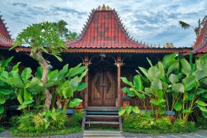 a building with a red roof with a wooden door at The Garden Villa in Sanur
