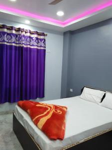 a bedroom with a bed with a purple curtain at Hotel Sunaina International in Gaya