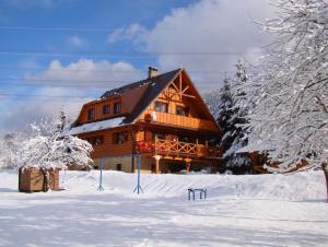 una grande casa in legno nella neve con gli alberi di Rekreačná chata pod Jedľovinou a Varín