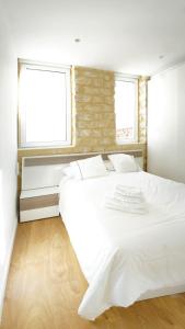 a white bed in a room with two windows at Alicante old city & beach appartment in Alicante