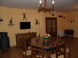 uma sala de jantar com uma mesa e uma televisão em Casa Rural El Botánico em Casatejada