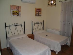 duas camas num quarto com lençóis brancos em Casa Rural El Botánico em Casatejada