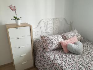ein Schlafzimmer mit einem Bett und einer Kommode mit einem Herzkissen in der Unterkunft Bay Home in Cádiz