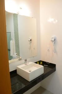 a bathroom with a white sink and a mirror at Excellence Plaza Hotel in Botucatu