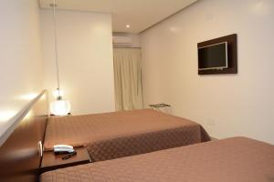 a hotel room with two beds and a television at Excellence Plaza Hotel in Botucatu