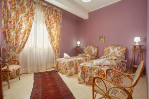 a bedroom with two beds and a chair and a window at Mergellina 10 in Marsala