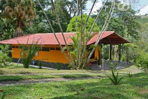 una casa amarilla con techo rojo en Tinamu Birding, en La Manuelita