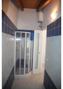 a bathroom with a shower with blue tiled walls at Costa Verde Apartment in Buggerru
