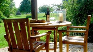 a wooden table with a bottle of wine and two chairs at JANISCHs Fewo im Spreewald, Terrasse, großer Garten und Blick inklusive in Unterspreewald