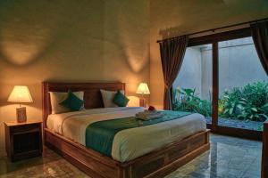 a bedroom with a large bed and a large window at The Garden Villa in Sanur
