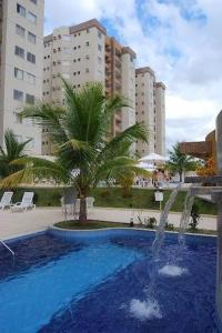 una piscina con una palmera y una fuente en Excelente apartamento de 02 quartos no Privê das Thermas II em Caldas Novas, en Caldas Novas