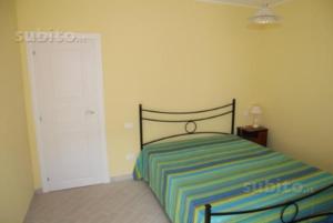 a bedroom with a striped bed and a door at Costa Verde Apartment in Buggerru