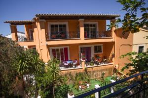 a large yellow house with tables and chairs at Apartments Mary in Agios Gordios