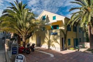 a yellow house with palm trees in front of it at BigBlue house in Veli Lošinj