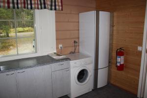 a kitchen with a refrigerator and a washing machine at Kuusitorppa in Varpaisjärvi