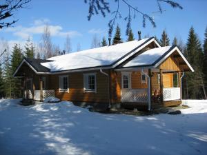 una cabaña de madera en la nieve con nieve en Kuusitorppa en Varpaisjärvi