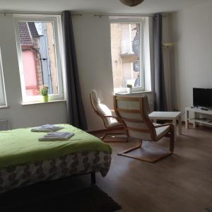 a bedroom with two chairs and a bed and two windows at Le Châtaignier in Forbach