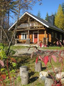 Mäkitorppa في Varpaisjärvi: كابينة خشب أمامها باب احمر