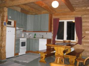 una cocina con armarios de madera y una mesa en una habitación en Mäkitorppa en Varpaisjärvi
