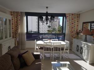 a living room with a table and chairs and a window at GEMELOS 26 APARTMENTS - Benidormland in Benidorm