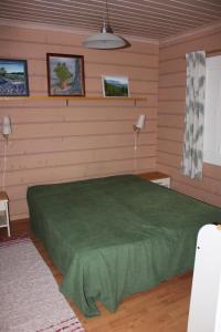 ein Schlafzimmer mit einem grünen Bett in einem Zimmer in der Unterkunft Kuusitorppa in Varpaisjärvi