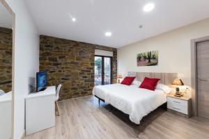 1 dormitorio con cama y pared de piedra en Petit Goierri, en Ormáiztegui