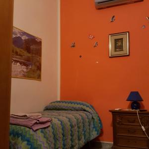 ブリンディジにあるbebvialataのオレンジ色の壁のベッドルーム1室、ベッド1台、ドレッサーが備わります。