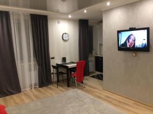 a living room with a table and a television on a wall at Квартира-Студия в Центре in Vinnytsya