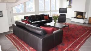 a living room with a black leather couch and a red rug at Chalet Brunner Penthouse in Wengen