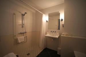 La salle de bains est pourvue d'un lavabo et d'une douche avec un miroir. dans l'établissement Clos de Vallombreuse, The Originals Relais (Relais du Silence), à Douarnenez